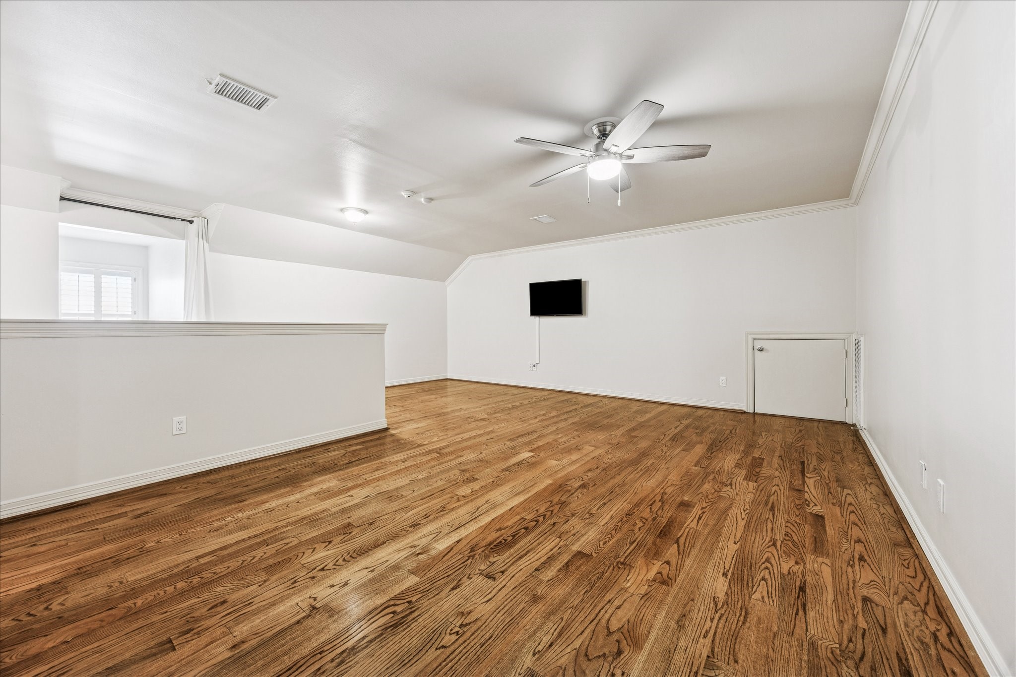 5823 Augusta Court Houston, TX 77057 - Photo 32 of 44 This spacious room on the third floor features polished hardwood floors, a ceiling fan, and a wall-mounted TV. It Ideal for a versatile living space, fourth bedroom, exercise room, study or media room.