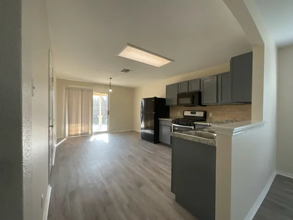 a kitchen with stainless steel appliances granite countertop a refrigerator stove top oven and sink with wooden floor
