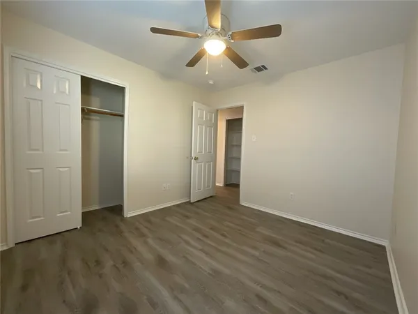 an empty room with wooden floor a ceiling fan and closet