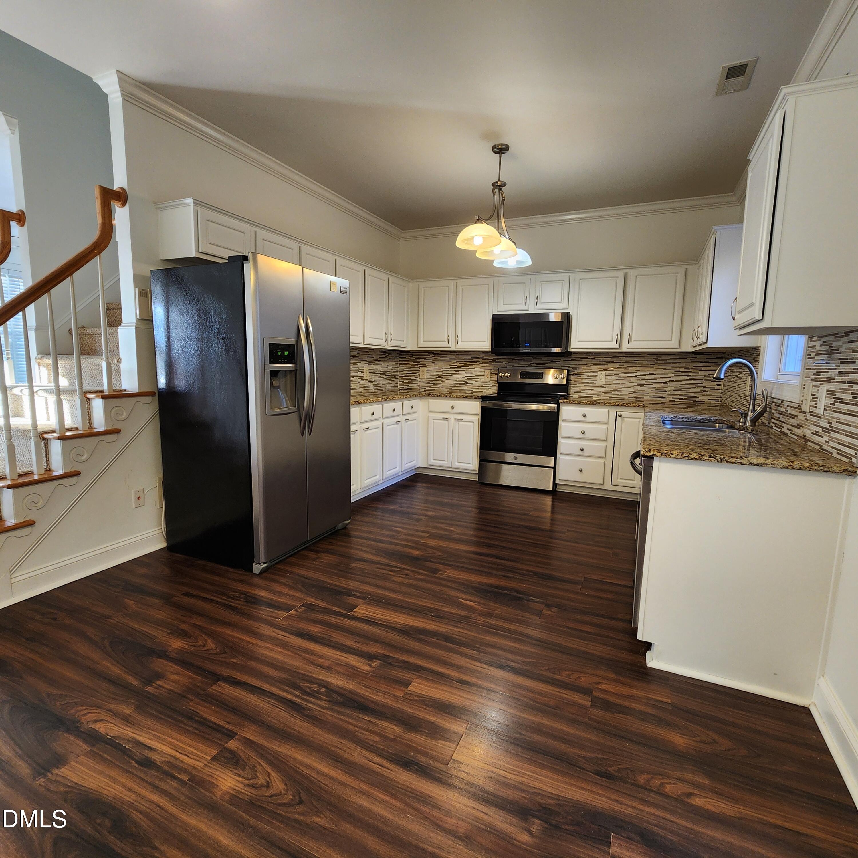 4916 Morning Edge Drive Raleigh, NC 27613 - Photo 6 of 26 a kitchen with stainless steel appliances kitchen island granite countertop a refrigerator a stove and a wooden floors