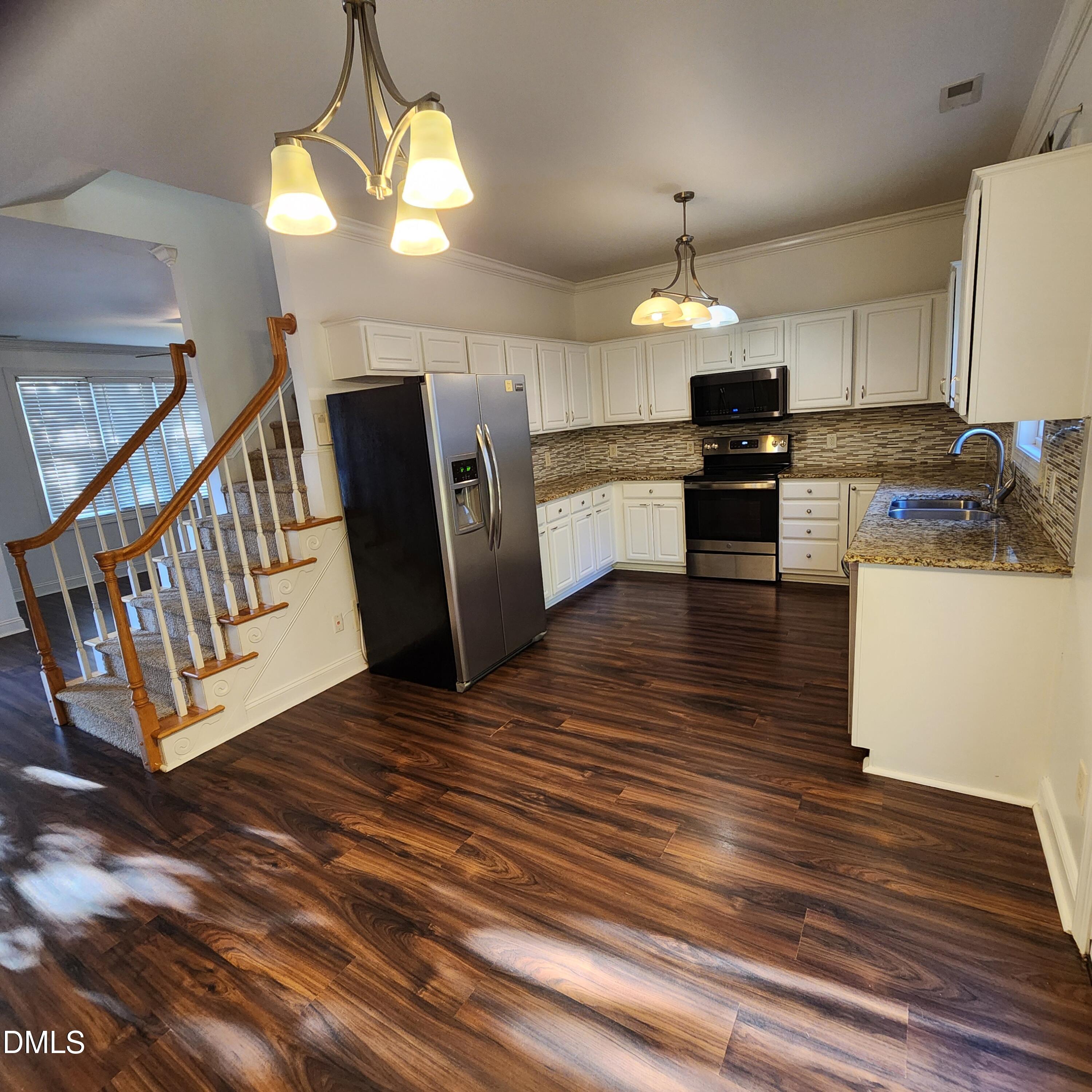 4916 Morning Edge Drive Raleigh, NC 27613 - Photo 7 of 26 a kitchen with stainless steel appliances kitchen island granite countertop a refrigerator a stove and a wooden floors