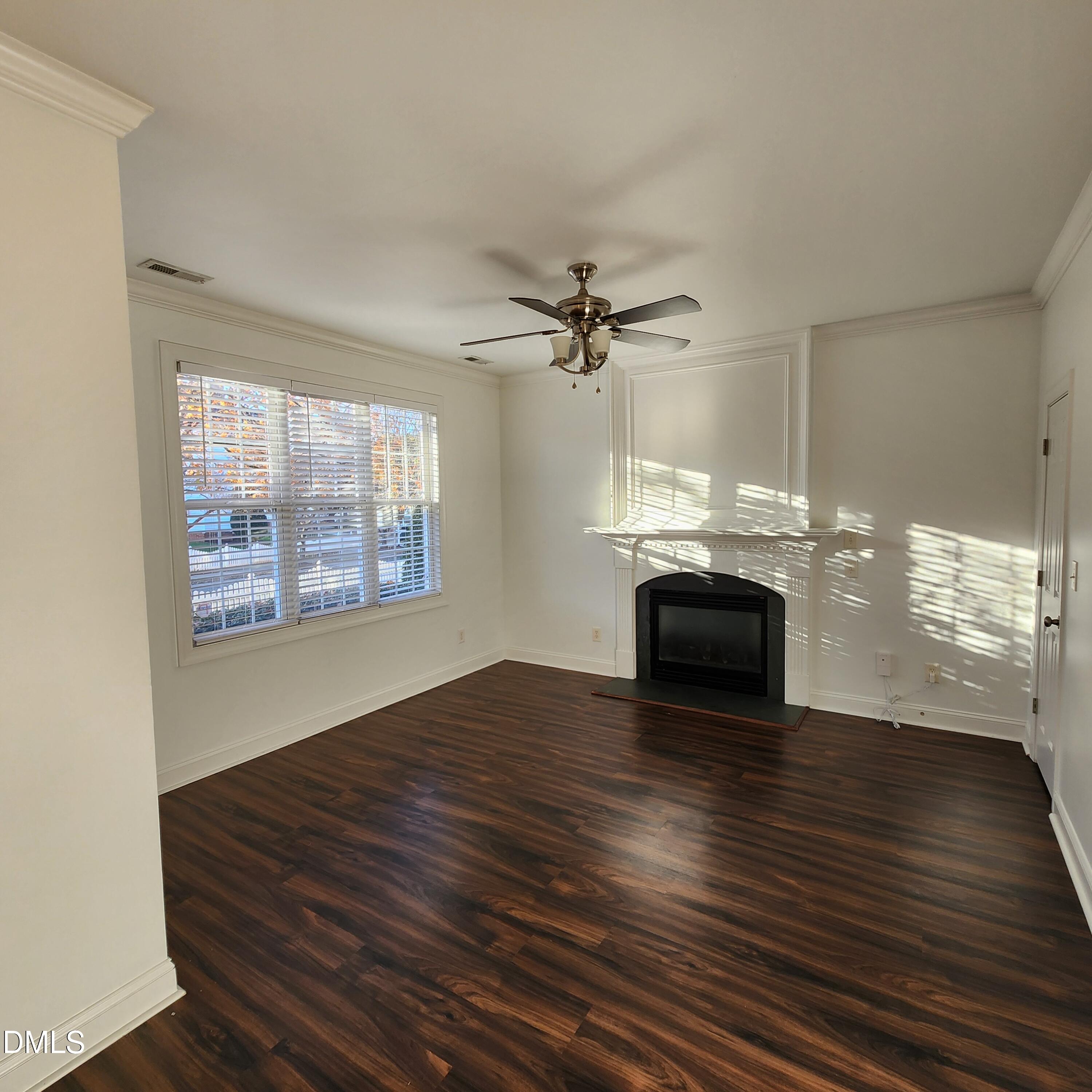 4916 Morning Edge Drive Raleigh, NC 27613 - Photo 9 of 26 an empty room with wooden floor fireplace and windows
