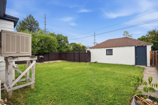 707 East 150 South Provo, UT 84606 - Photo 27 of 31 Expansive fenced backyard featuring a detached garage with a dark-paneled door, a brown shingle roof, and a concrete walkway