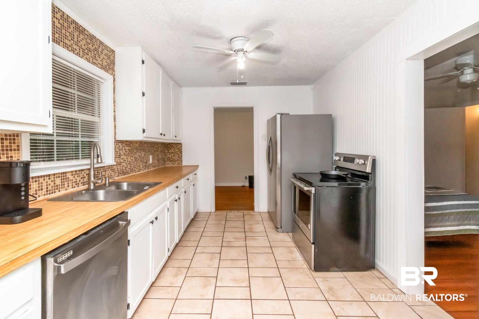 61 Nack Lane Mobile, AL 36608 - Photo 10 of 25 Kitchen with sink, ceiling fan, white cabinetry, backsplash, and stainless steel appliances