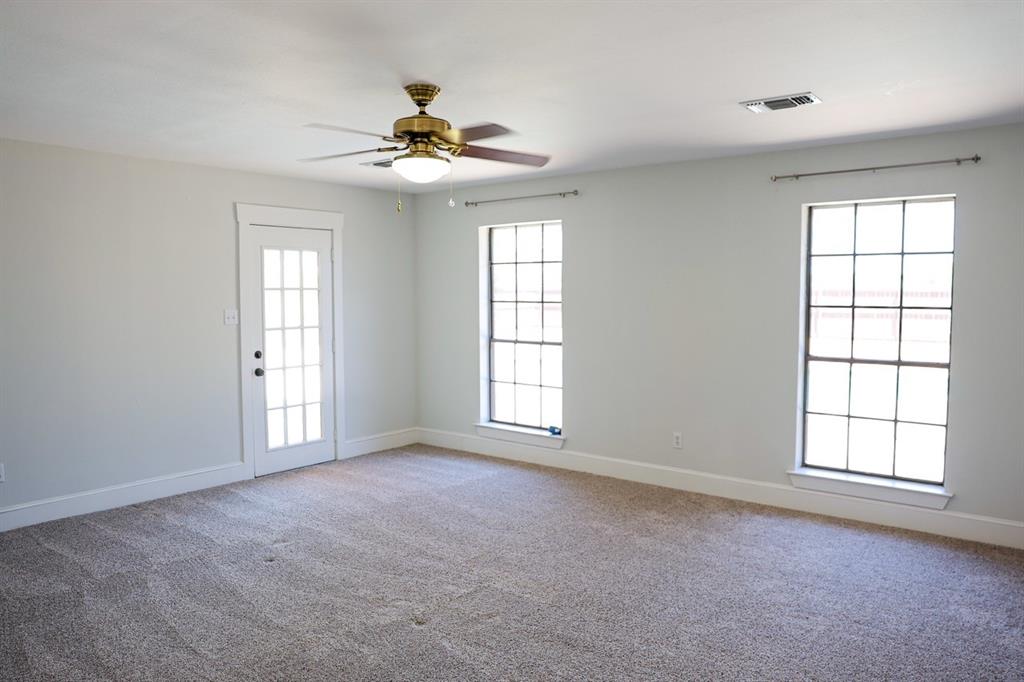 10575 Friendship Road Pilot Point, TX 76258 - Photo 28 of 32 Spacious interior room featuring light gray walls, plush carpeting, a ceiling fan with integrated lighting, two multi-pane windows, and a multi-pane glass door