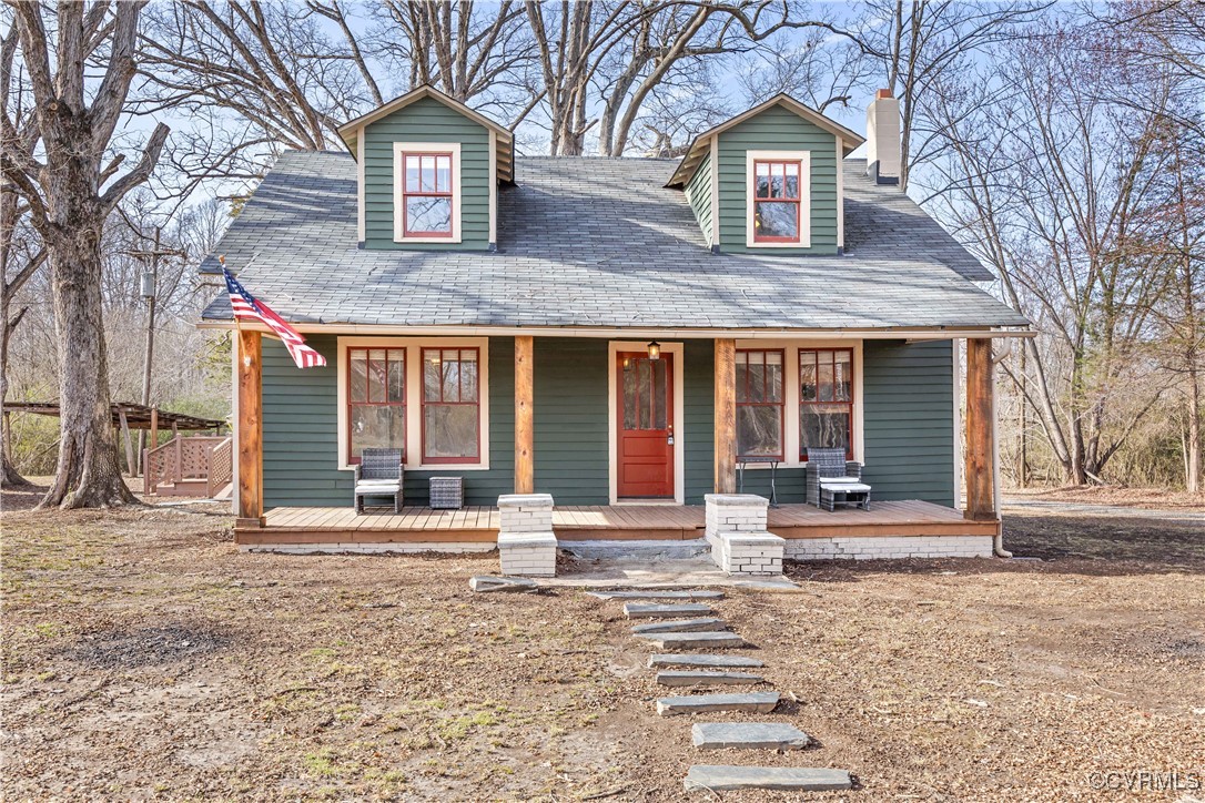 View of front facade with covered porch and a chim