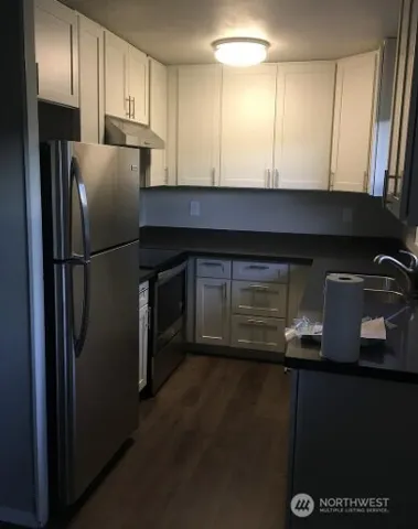 a kitchen with metallic refrigerator and wooden cabinets