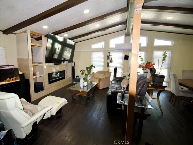 a living room with furniture kitchen view and a wooden floor