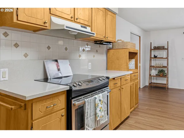 a kitchen with stainless steel appliances granite countertop a refrigerator a sink dishwasher and wooden cabinets with wooden floor