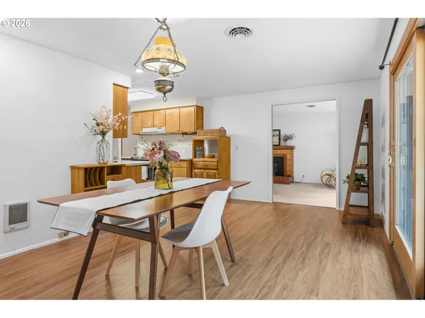 a dining room with wooden floor a chandelier a wooden table and chairs