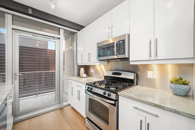 a kitchen with stainless steel appliances granite countertop white cabinets and window