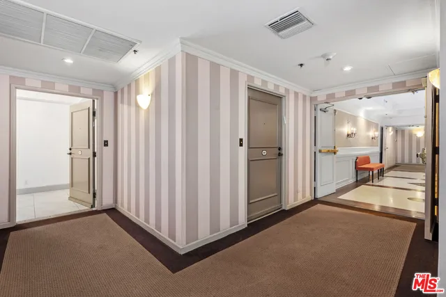 an empty room with a chandelier fan and wooden floor