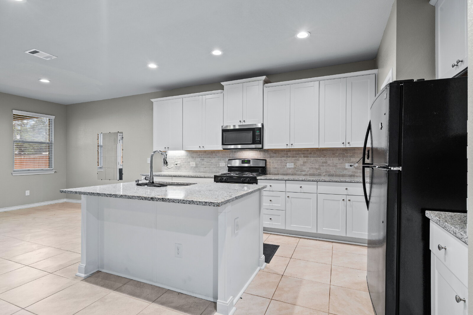 204 Tulum Terrace Leander, TX 78641 - Photo 9 of 22 Kitchen featuring white cabinets, stainless steel appliances, a center island with sink, light stone counters, and recessed lighting