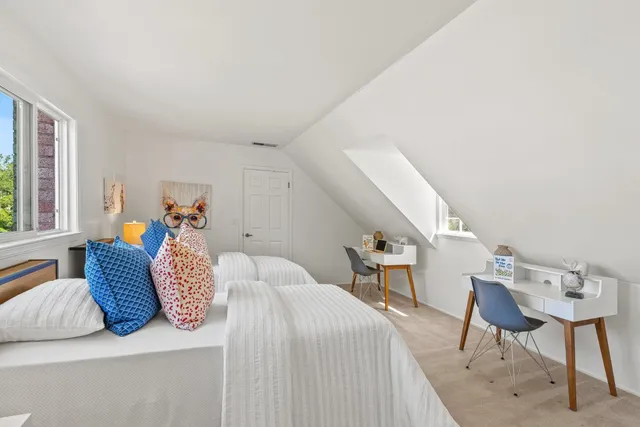 a bedroom with a bed a chair and potted plant on the table