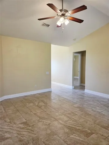 a view of an empty room with chandelier fan