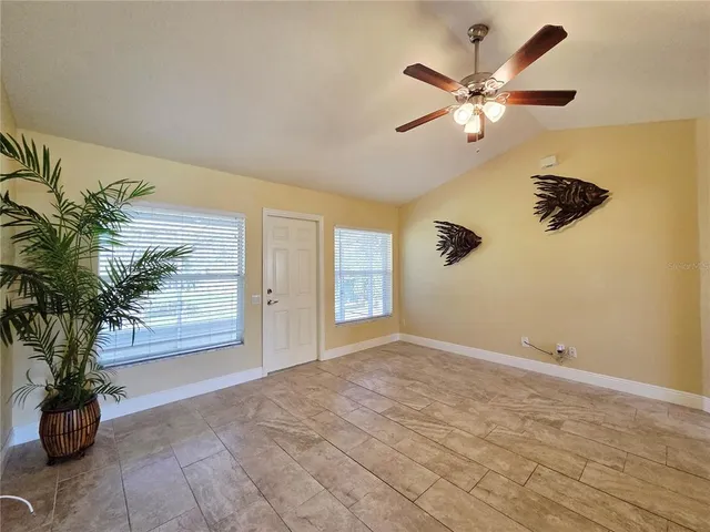 a view of an empty room with a window and a chandelier fan