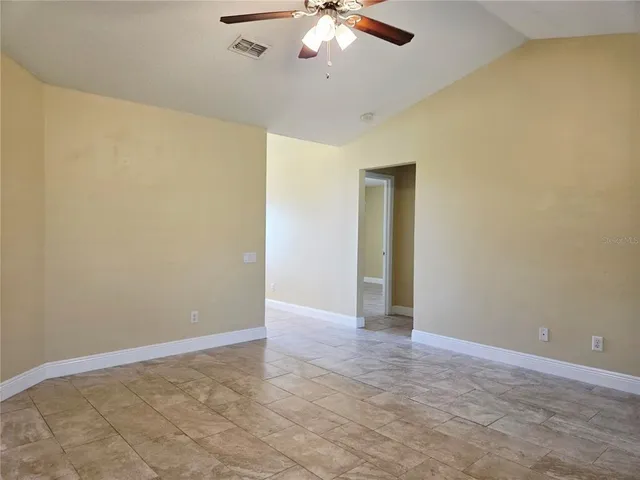 a view of an empty room with a chandelier fan