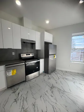 a kitchen with granite countertop a refrigerator and a stove top oven