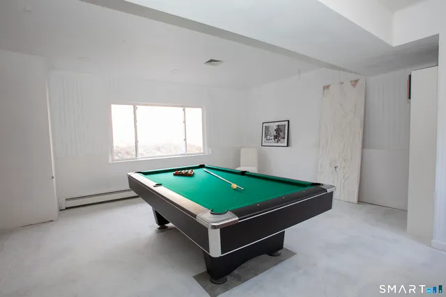 a room with wooden floor pool table furniture and windows