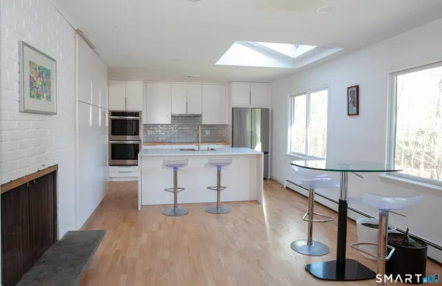 a open kitchen with kitchen island a sink wooden floor and dining table chairs