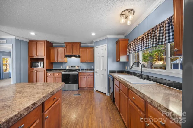 a kitchen with stainless steel appliances granite countertop a sink a stove and a wooden floors