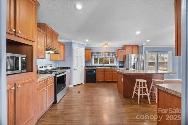 a kitchen with stainless steel appliances granite countertop a stove top oven a sink dishwasher and a oven with wooden floor