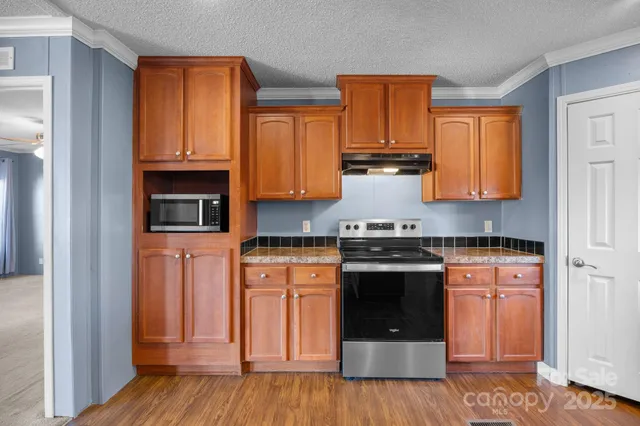 a kitchen with granite countertop wood cabinets stainless steel appliances and a window