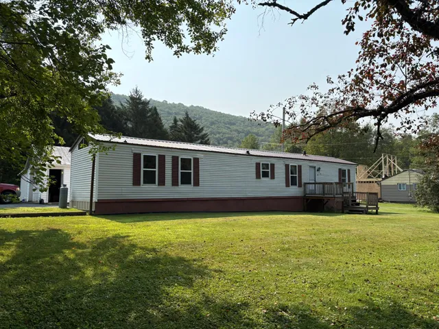 a view of a white house with a small yard and parking space