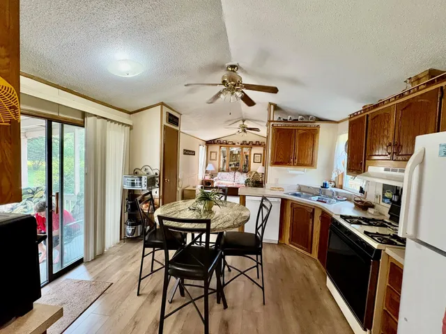 a kitchen with stainless steel appliances kitchen island granite countertop a table chairs in it and wooden floors