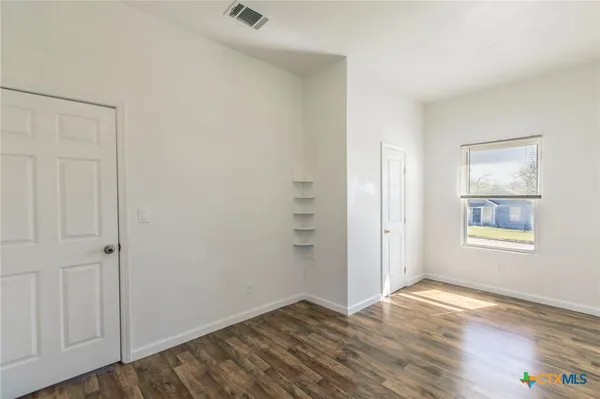 an empty room with wooden floor and windows
