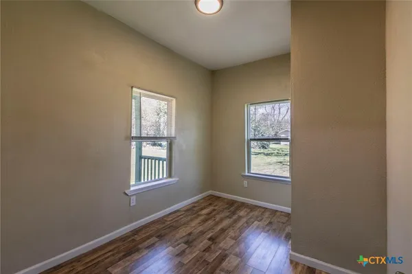 a view of an empty room with window and wooden floor