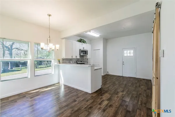 a kitchen with white cabinets and window