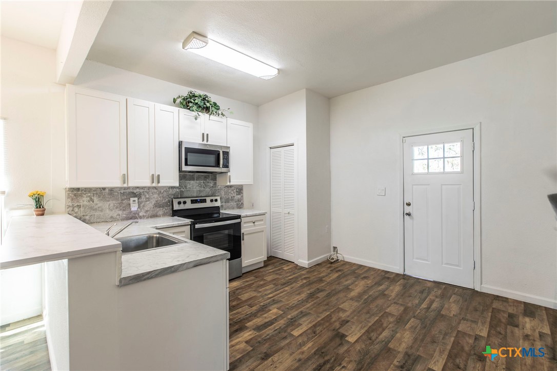 914 South 2nd Street Temple, TX 76504 - Photo 7 of 25 a kitchen with granite countertop white cabinets and stainless steel appliances