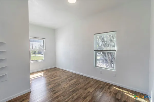 an empty room with wooden floor and windows