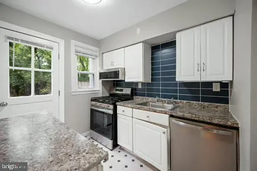 a kitchen with stainless steel appliances granite countertop a stove a sink and a microwave