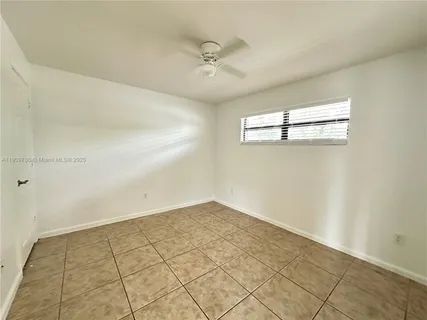an empty room with windows and ceiling fan