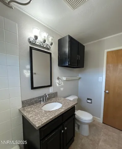 a bathroom with a granite countertop sink a toilet and mirror