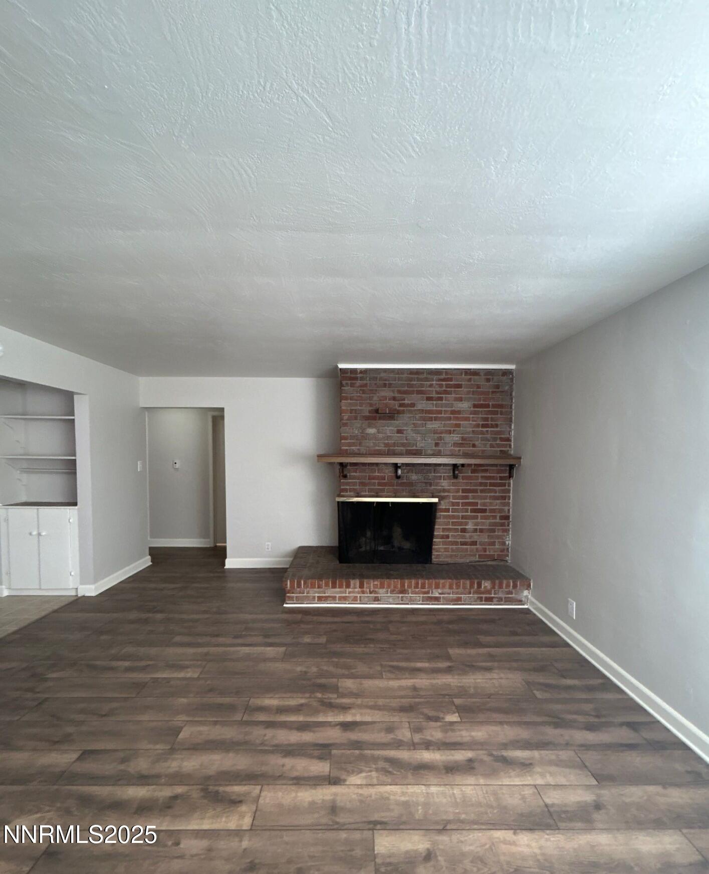660 Kirman Avenue Reno, NV 89502 - Photo 4 of 17 a view of an empty room with wooden floor fireplace and a window