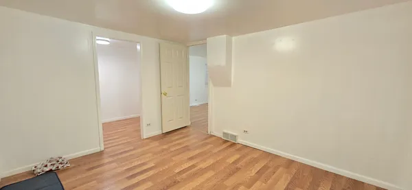a view of an empty room with wooden floor and closet