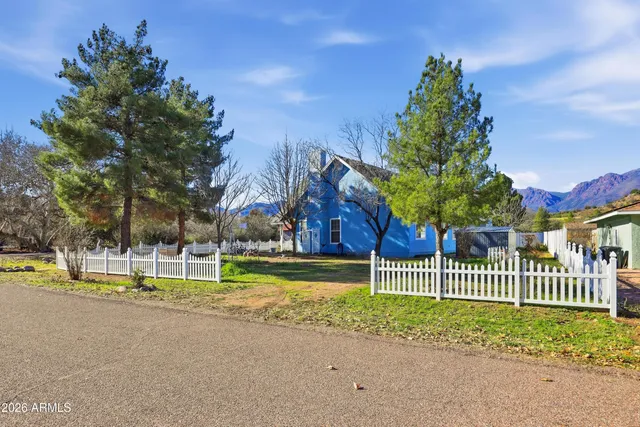 a view of a house with a small yard and large trees