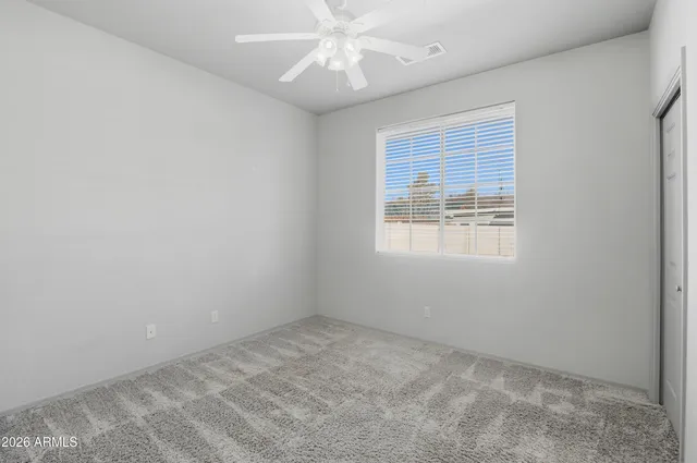 an empty room with a chandelier fan and windows