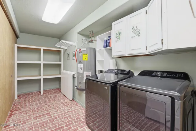 a utility room with stainless steel appliances granite countertop a sink a stove a washer and dryer