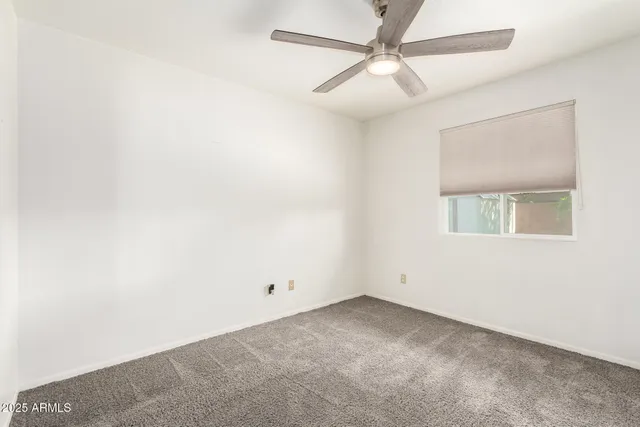 an empty room with a ceiling fan and a window