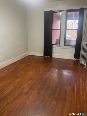 a view of an empty room with a window and wooden floor