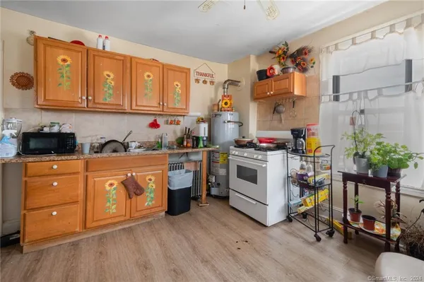 a kitchen with stainless steel appliances granite countertop a stove a sink dishwasher and white cabinets with wooden floor