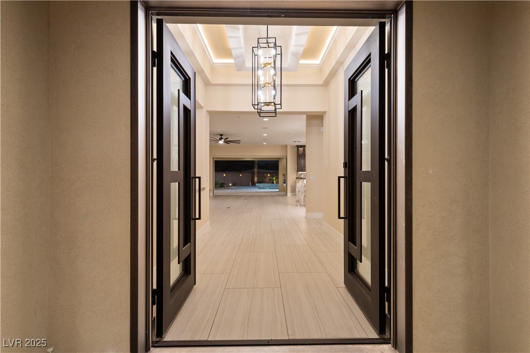 9865 Bright Angel Way Las Vegas, NV 89149 - Photo 17 of 98 Corridor featuring a raised ceiling, baseboards, a chandelier, and light tile patterned floors