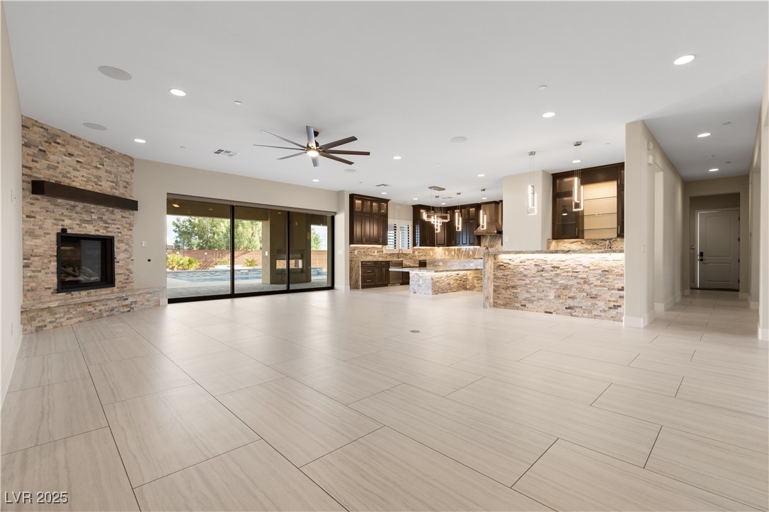 9865 Bright Angel Way Las Vegas, NV 89149 - Photo 19 of 98 Unfurnished living room with a large fireplace, recessed lighting, and ceiling fan