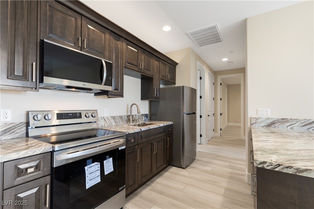 9865 Bright Angel Way Las Vegas, NV 89149 - Photo 79 of 98 Casita #2 Kitchen with stainless steel appliances, a sink, dark brown cabinets, light wood finished floors, and recessed lighting