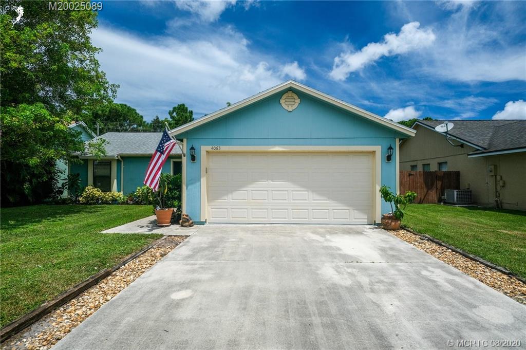 4063 Southeast Jacaranda Street Stuart, FL 34997 - Photo 31 of 34 a front view of a house with a yard and garage