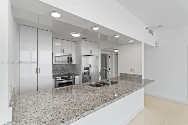 a kitchen with stainless steel appliances kitchen island granite countertop a refrigerator and a sink